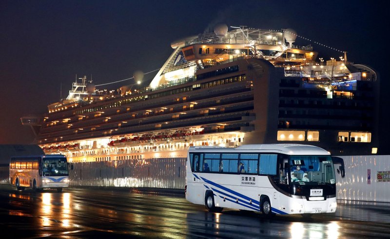 The Associated Press CRUISE SHIP: Buses carrying U.S. passengers who were aboard the quarantined cruise ship the Diamond Princess, seen in background, leaves Yokohama port, near Tokyo, early Monday. The cruise ship was carrying nearly 3,500 passengers and crew members under quarantine.