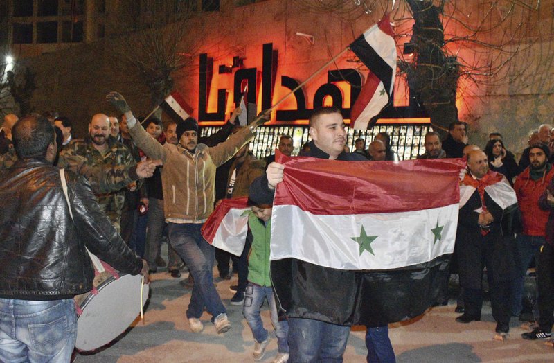 The Associated Press CELEBRATING: In this photo released by the Syrian official news agency SANA, Syrians celebrate as they hold their national flags in Aleppo province, Syria, Monday. On Monday Syria's military announced its troops have regained control of territories in northwestern Syria "in record time," vowing to continue to chase armed groups "wherever they are."