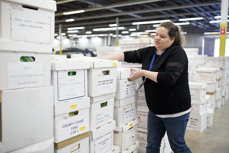 Tiffany Underwood, office manager, moves boxes of old probate cases, marriage licenses and voter records going back to late 1800s in 2018 at the Benton County Clerk's office in the old Kmart building in Rogers. (File Photo/NWA Democrat-Gazette/Charlie Kaijo)