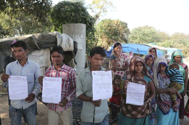 People display notices Tuesday that they received evicting them from their homes near a stadium in Ahmedabad, India. One resident said they were told to leave “because some important leader is visiting this city for a day.” More photos at arkansasonline.com/219wall/.
(AP/Ajit Solanki)