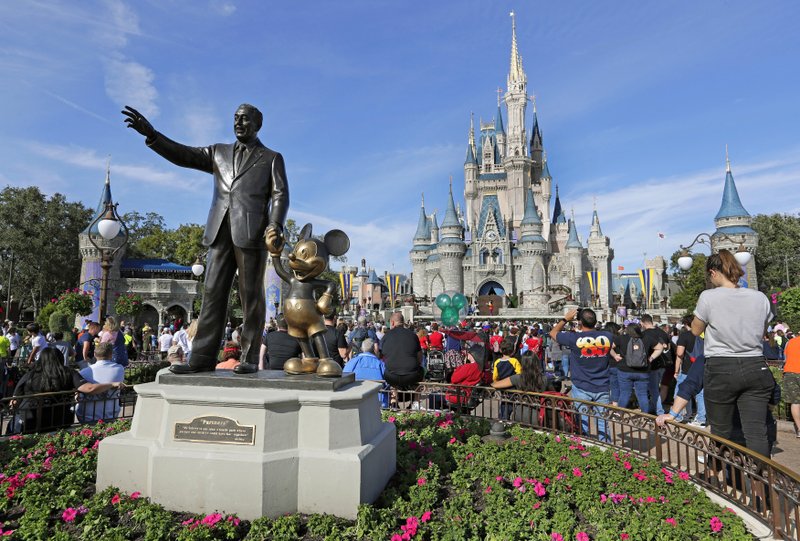 PARTNERS: In this Jan. 9, 2019 photo, guests watch a show near a statue of Walt Disney and Micky Mouse in front of the Cinderella Castle at the Magic Kingdom at Walt Disney World in Lake Buena Vista, Fla. Disney officials said Monday, that the iconic Cinderella Castle would be renovated over the next several months. The most noticeable changes will be the addition of gold trim to most of the castle and the darkening of the blue hue on the castle's turrets. Work on the castle will last through the summer.