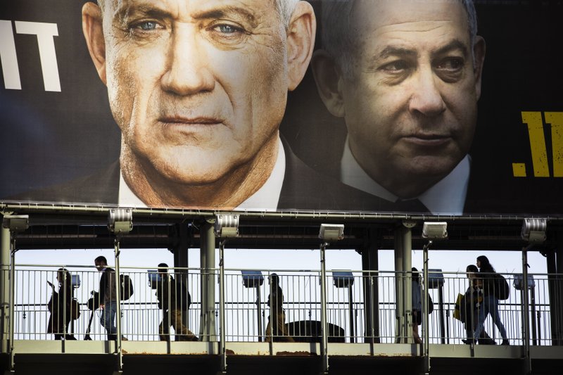 People walk on a bridge Tuesday under an election campaign billboard for the Blue and White party, the opposition party led by Benny Gantz (left) in Ramat Gan, Israel. Prime Minister Benjamin Netanyahu of the Likud party is pictured at right.
(AP/Oded Balilty)