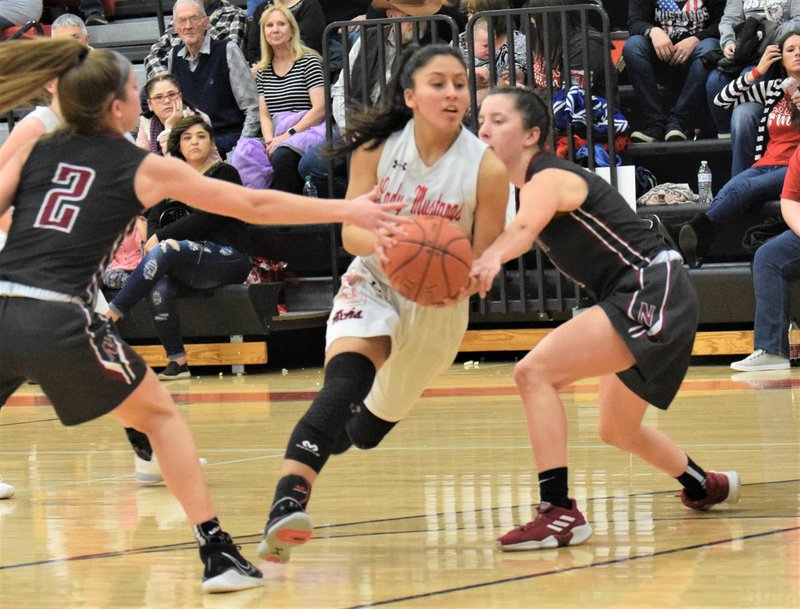 RICK PECK/SPECIAL TO MCDONALD COUNTY PRESS McDonald County's Rita Santillan drives past Nevada's Calli Beshore (2) and Lindley Ferry during the Lady Mustangs' 58-22 loss on Feb. 14 at MCHS.
