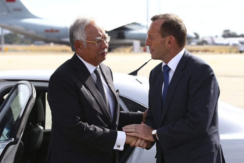 FILE - In this April 3, 2014, file photo, Australian then Prime Minister Tony Abbott, right, shakes hands with Malaysian then Prime Minister Najib Razak as Razak prepares to depart Australia after his visit during the search of the missing Malaysia Airlines flight MH370 at Perth International Airport, Australia.  (Paul Kane/Pool Photo via AP, File)