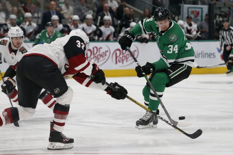 Arizona Coyotes defenseman Alex Goligoski (33) and Dallas Stars right wing Denis Gurianov (34) reach for the puck during the first period of Wednesday's game in Dallas. - Photo by Michael Ainsworth of The Associated Press