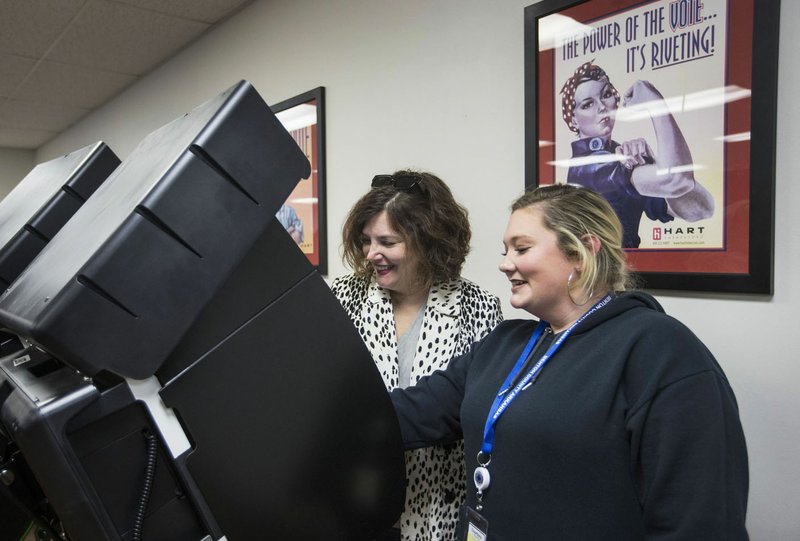 Courtney Leemasters (right), Benton County deputy clerk, sets up Julie Heimeshoff of Bella Vista with a voting machine Friday during early voting in the primary election at the Benton County clerk's office in Bentonville. Go to nwaonline.com/200222Daily/ for today's photo gallery. (NWA Democrat-Gazette/Ben Goff)