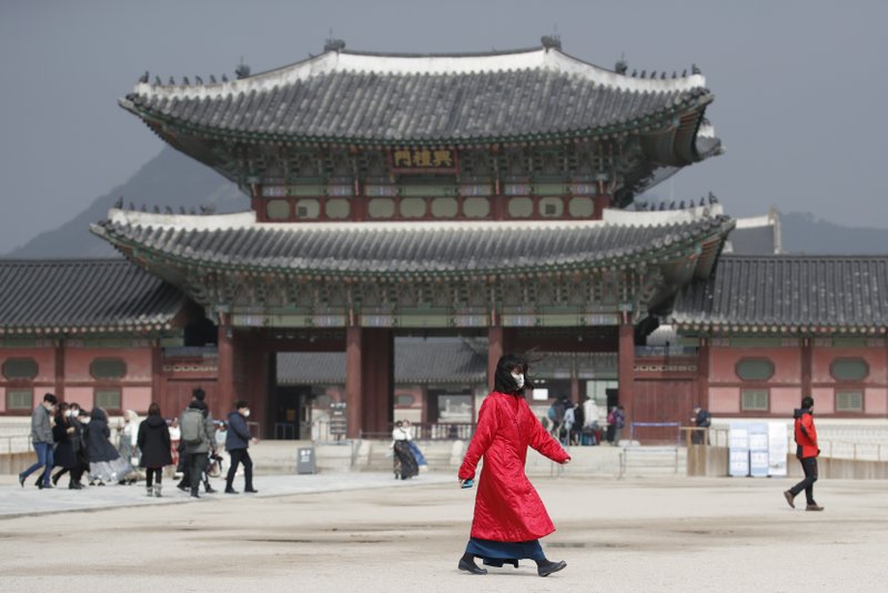 A woman wearing a face mask walks at the Gyeongbok Palace, one of South Korea's well-known landmarks, in Seoul, South Korea, on Saturday. South Korea on Saturday reported eight-fold jump in viral infections in four days with more than 400 cases, most of them linked to a church and a hospital in and around the fourth-largest city where schools were closed and worshipers and others told to avoid mass gatherings. - AP Photo/Lee Jin-man