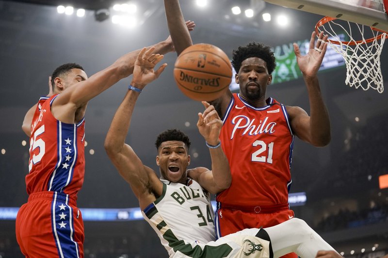 Milwaukee Bucks' Giannis Antetokounmpo is fouled as he drives between Philadelphia 76ers' Ben Simmons and Joel Embiid (21) during the first half of Saturday's game in Milwaukee. - Photo by Morry Gash of The Associated Press