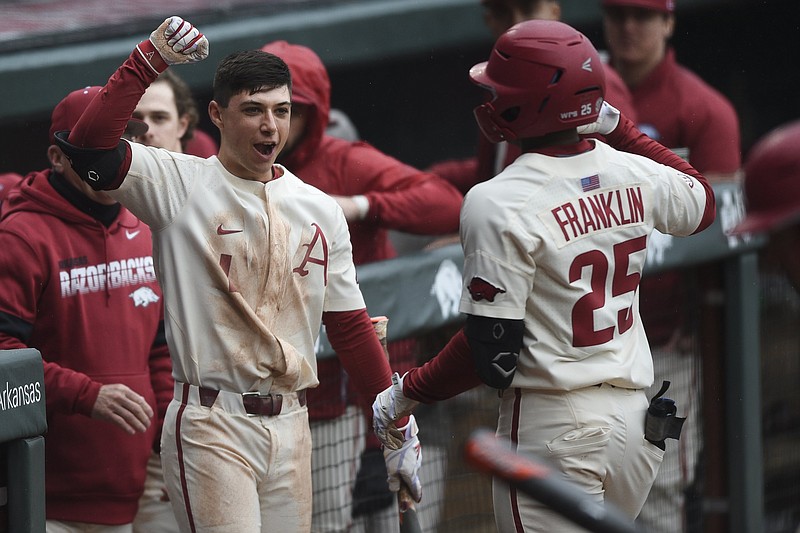 Arkansas outfielder Christian Franklin (25) is greeted by second baseman Robert Moore in the dugout following a home run, Sunday, Feb. 24, 2020 during a baseball game at Baum-Walker Stadium in Fayetteville. 