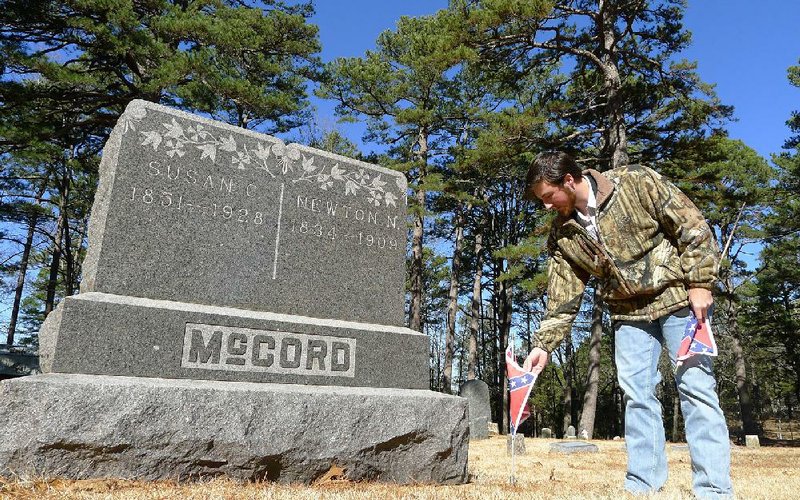 Koltin Massie, commander of the Sons of Confederate Veterans’ Seaborn Jones Cotten Camp 2303, puts Confederate flags on the graves of Confederate veterans Friday in Eureka Springs Cemetery. Seaborn Jones Cotten, who fought for the Confederacy, was Massie’s fourth great-grandfather. He is buried in Louisiana.
(Arkansas Democrat-Gazette/Bill Bowden)