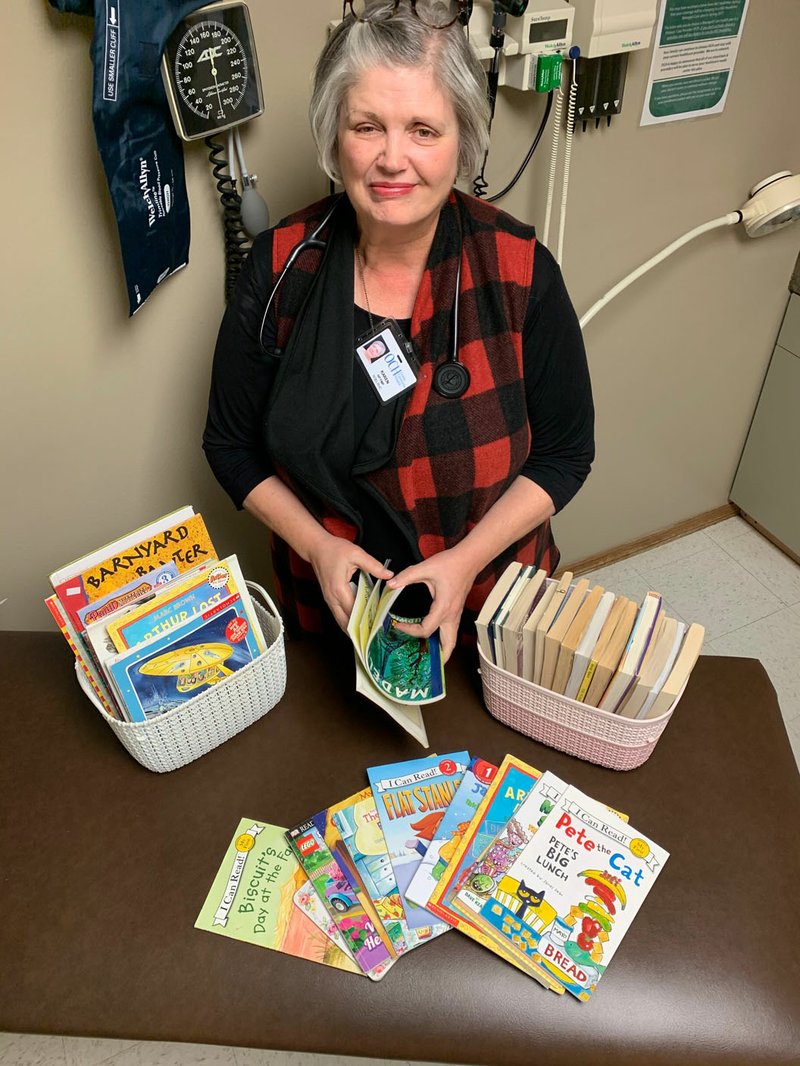 Photo submitted Known as the "Book Nurse," Karen Madsen displays a gathering of books she distributes to children who visit the Noel clinic of the Ozarks Community Hospital.