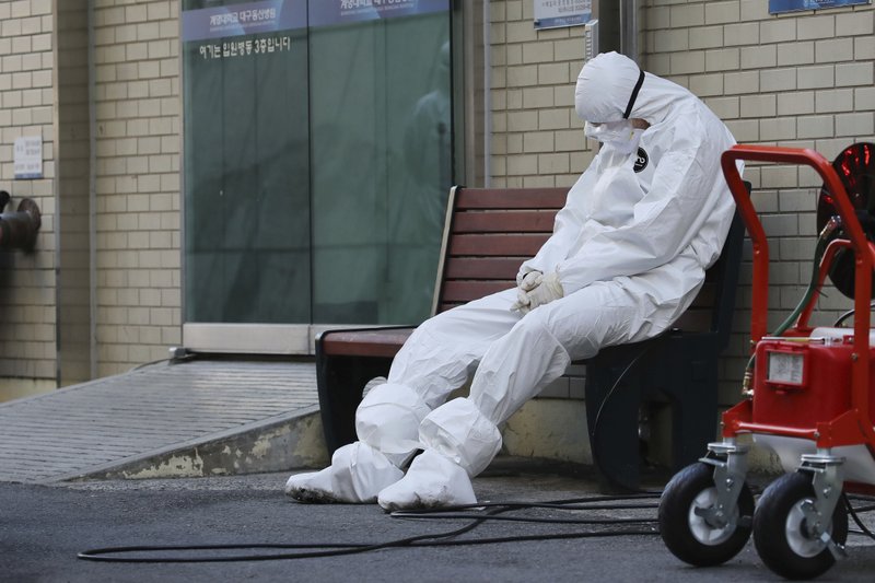 A member of the medical team takes a rest outside a hospital in Daegu, South Korea, on Sunday. South Korea's president has put his country on its highest alert for infectious diseases, saying Sunday that officials should take "unprecedented, powerful" steps to fight a viral outbreak. - Im Hwa-young/Yonhap via AP