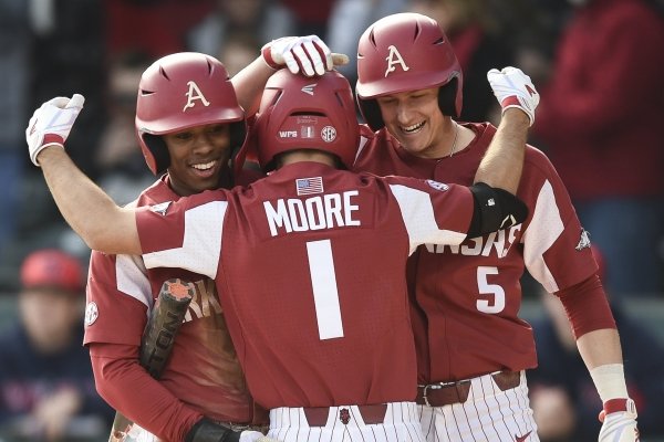 Arkansas outfielder Christian Franklin (25) and infielder Jacob Nesbit (5) react as infielder Robert Moore (1) runs home for a score Saturday at Baum-Walker Stadium in Fayetteville.