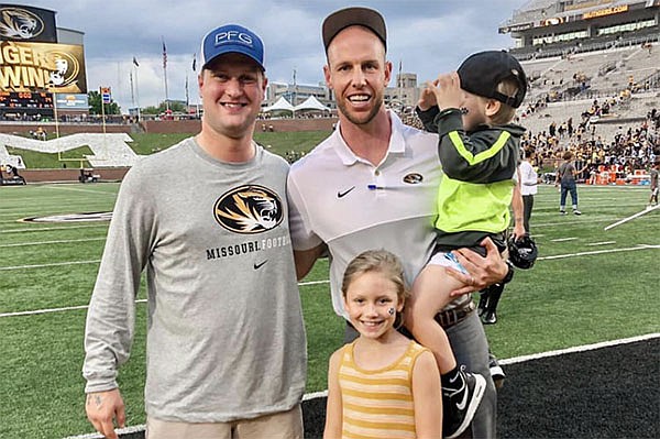 Travis Gipson (left) is shown with Joseph Henry and Henry's children Ford and Linley following a football game in Columbia, Mo. 