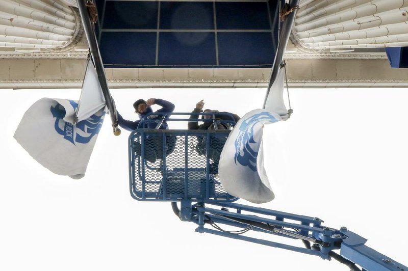 FILE - Dylan Curtis, left, and his co-worker John Sherrill, with Little Rock Awning untangle flags after installing a canopy at North Little Rock city hall on Main Street in that city, on Feb. 26, 2020.  (Arkansas Democrat-Gazette/John Sykes Jr.)