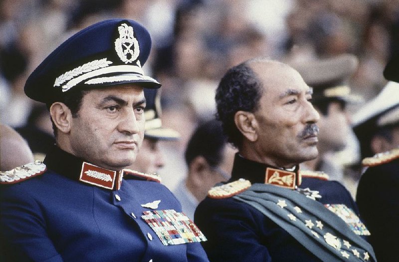 Hosni Mubarak (left) sits on the reviewing stand on Oct. 6, 1981, with Egyptian President Anwar Sadat during a military parade just before soldiers opened re, killing Sadat and injuring Mubarak. Mubarak, then vice president, took over as president. At right, Mubarak attends a hearing in Cairo in September 2013 during a retrial on murder and corruption charges. Mubarak was ultimately exonerated. More photos at arkansasonline.com/226mubarak/. 
(AP le photos) 