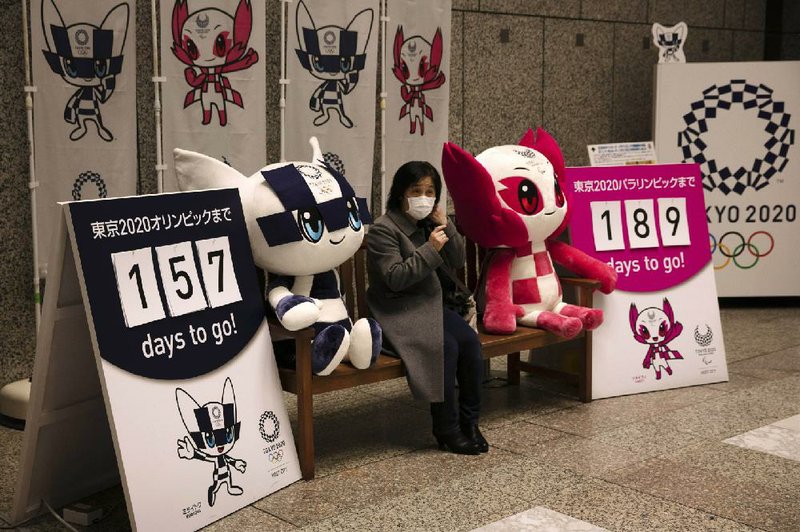 A woman in a mask sits before taking pictures with the mascots of the Tokyo 2020 Olympics and Paralympics in Tokyo. The coronavirus outbreak has raised concerns about whether the Olympics, which start in July, will be held.
(AP/Jae C. Hong)