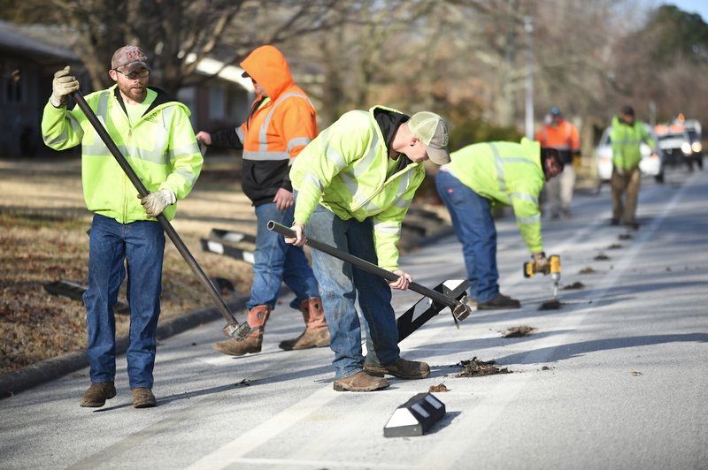 Workers remove the rubber bumpers on Rolling Hills Drive Thursday, Feb. 27, 2020, in Fayetteville. (NWA Democrat-Gazette/David Gottschalk)