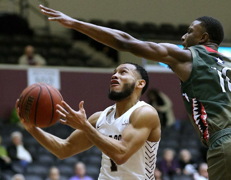 UALR sophomore guard Markquis Nowell (left) drives past Louisiana-Monroe sophomore guard Langston Powell during the Trojans’ victory over the Warhawks on Thursday night at the Jack Stephens Center in Little Rock. Nowell made seven three-pointers and led all scorers with 32 points.
(Arkansas Democrat-Gazette/Thomas Metthe)