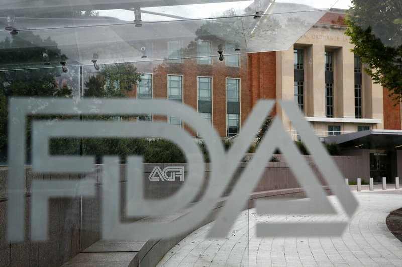 FILE - This Aug. 2, 2018, file photo shows the U.S. Food and Drug Administration building behind FDA logos at a bus stop on the agency's campus in Silver Spring, Md. Health officials reported the first U.S. drug shortage tied to the viral outbreak that is disrupting production in China, but they declined to identify the manufacturer or the product. The Food and Drug Administration said late Thursday, Feb. 27, 2020, that the drug's maker contacted health officials recently about the shortage, which it blamed on a manufacturing issue with the medicine's key ingredient. (AP Photo/Jacquelyn Martin, File)