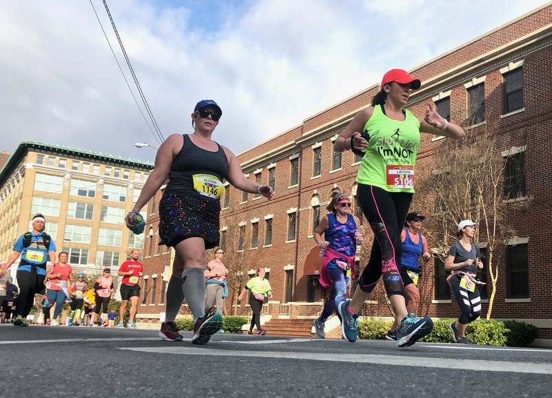 Marathoner No. 1146, Allyson Russell of Rockville, Md., and half-marathoner 5106, Latisha Lunsford of Equality, Ill., pass Scott Street headed east on Fourth during the 2020 Little Rock Marathon. Spectators read Lunsford’s shirt and shouted, “You’re almost there.” (Arkansas Democrat-Gazette/Celia Storey)