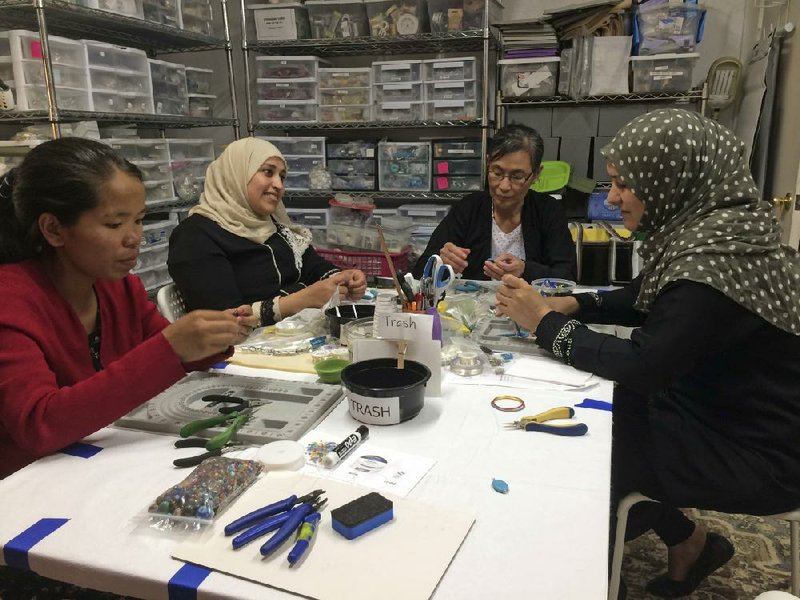 This May 15, 2019 photo shows A Little Something participants Khei Hung from Burma, left, Sabah Almobarak from Syria, Eh Gay Ju from Burma, and Mounira Kuru from Syria, as they work through frustration and creative challenges in their first lesson making wire-wrapped necklace pendants in Aurora, Colo. A Little Something helps women refugees turn their crafts into dollars. Around the world there are organizations that use crafting and the arts as tools to help refugees build community and learn new skills. (Sharon L. McCreary via AP)