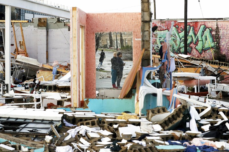 People are reflected in a mirror of a building destroyed by storms Tuesday, March 3, 2020, in Nashville, Tenn. Tornadoes ripped across Tennessee early Tuesday, shredding buildings and killing multiple people.