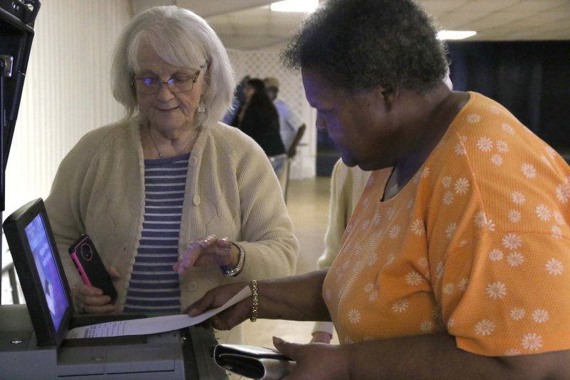Nadine Island inserts her ballot with the help of poll worker Dorothy Bale March 3 at the Union County Fairgrounds voting center. Many poll workers and voters reported issues with the machines early on. 