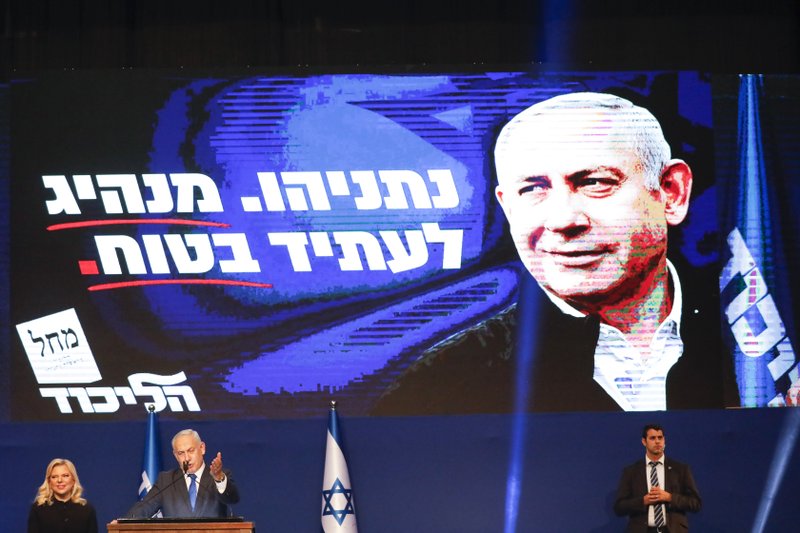 Israeli Prime Minister Benjamin Netanyahu, accompanied by his wife Sara, addresses his supporters after first exit poll results for the Israeli elections at his party's headquarters in Tel Aviv, Israel, Monday, March 2, 2020. (AP Photo/Ariel Schalit)