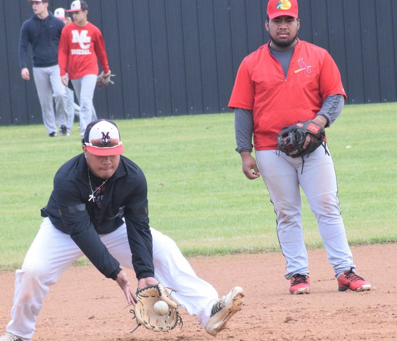 RICK PECK/SPECIAL TO MCDONALD COUNTY PRESS Omar Manuel fields a ground ball as Junior Eliam looks on during the first day of baseball practice on March 2 at McDonald County High School.