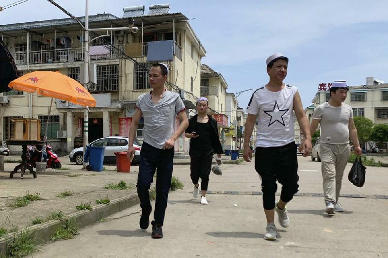 Residents of the Hui Muslim ethnic minority walk in a neighborhood near an OFILM factory in Nanchang in eastern China’s Jiangxi province in June. (AP/Ng Han Guan) 