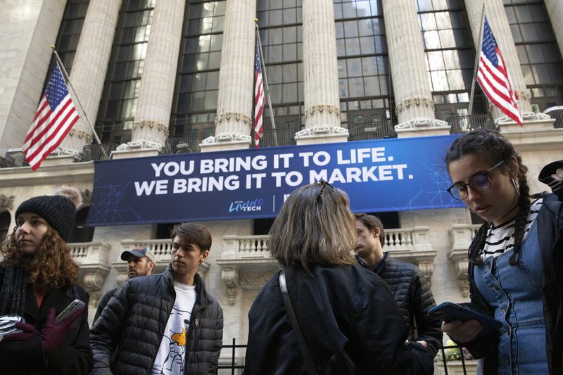FILE - In this Monday, March 9, 2020 file photo, people stop to look at the New York Stock Exchange.

