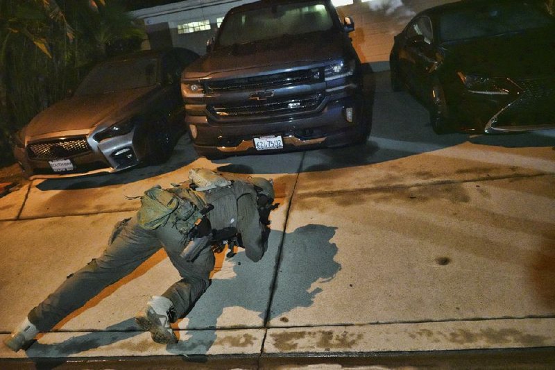 A DEA agent checks under a car early Wednesday during a raid in Diamond Bar, Calif. Agents arrested Victor Ochoa, who officials said is a stash house manager for the Jalisco New Generation Cartel.
(AP/Richard Vogel)
