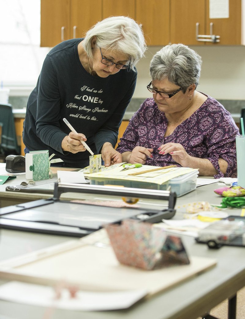 Jane Para (left) gives Pat Hufford, both of Rogers, advice on completing her photo album Friday, March 13, 2020, during the weekly scrapbooking class at the Rogers Adult Wellness Center. The center plans to remain open Friday and Saturday, but announced that it will temporarily close starting Monday due to concert about the spread of COVID-19. Check out nwaonline.com/200314Daily/ for today&#xc3;&#xa2;&#xe2;&#x201a;&#xac;&#xe2;&#x201e;&#xa2;s photo gallery. (NWA Democrat-Gazette/Ben Goff)