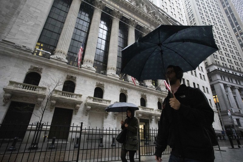 People walk in the rain as they pass the the New York Stock Exchange, Friday, March 13, 2020. European stocks rose Friday and Wall Street was set to gain on the open after turbulent trading in Asia and a day after the market's worst session in over three decades. (AP Photo/Mark Lennihan)

