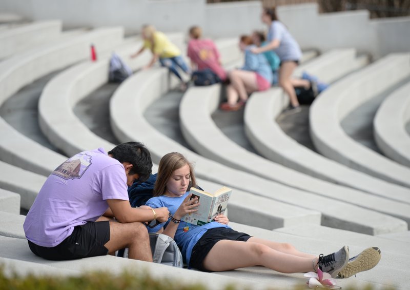 Friends Danny Santillan (left) and Lauren Skartvedt, both University of Arkansas undergraduate students from Russellville, relax Thursday in the Chi Omega Greek Theater on the university campus in Fayetteville. The pair plan to head home to Russellville today after the university canceled in-person classes Thursday and plans to begin online instruction Monday in response to the coronavirus pandemic. Go to nwaonline.com/200313Daily/ for today’s photo gallery.
(NWA Democrat-Gazette/Andy Shupe)