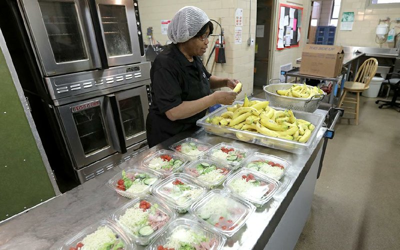 Eddie Mae Finley, cafeteria manager at Williams Elementary School, prepares the Little Rock School District’s “grab-and-go-lunch” of chef salad, fruit and milk. All district schools offered the food for pickup Friday.
(Arkansas Democrat-Gazette/John Sykes Jr.)
