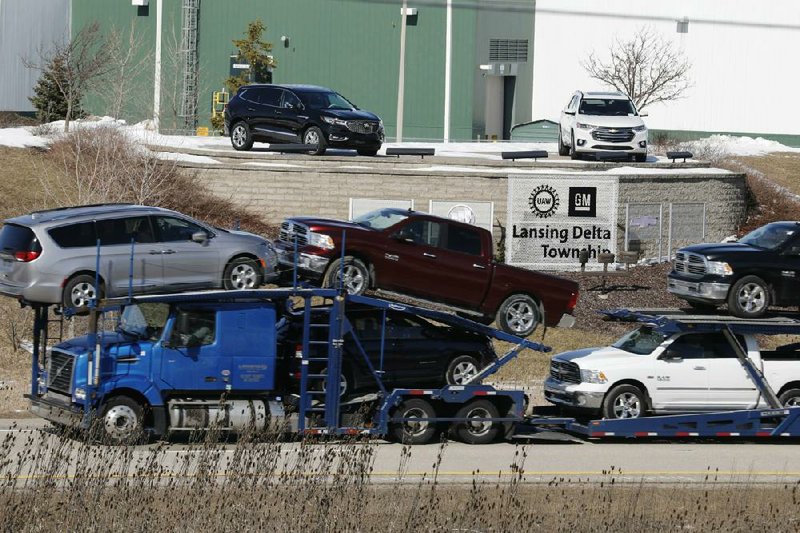 A truck hauling Fiat Chrysler vehicles passes a General Motors Co. assembly plant last month in Lansing, Mich. A Fiat Chrysler worker in Indiana has tested positive for the covid-19 illness.
(Bloomberg News/Jeff Kowalsky)