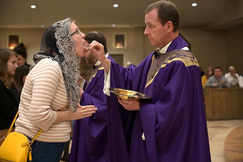 Jenny Geiselhart takes communion from Pastor Erik Pohlmeier at Christ the King Catholic Church during the last Mass the church will hold until further notice on Sunday, March 15, 2020. Though they won't hold public Mass, the church plans to livestream a noon service every day starting next week, and will remain open for private prayer and will have priests available for confession.


(Arkansas Democrat-Gazette / Stephen Swofford)