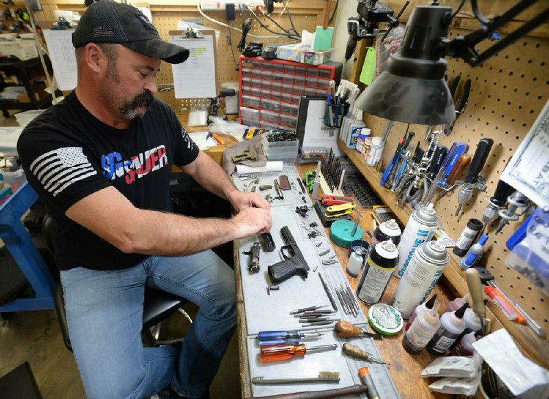 Burton Chaney, a gunsmith at Wilson Combat, disassembles a Sig Sauer handgun at the company factory in Berryville. Wilson is working with Sig Sauer to offer customized versions of the popular brand’s handguns. (NWA Democrat-Gazette/Andy Shupe) 
