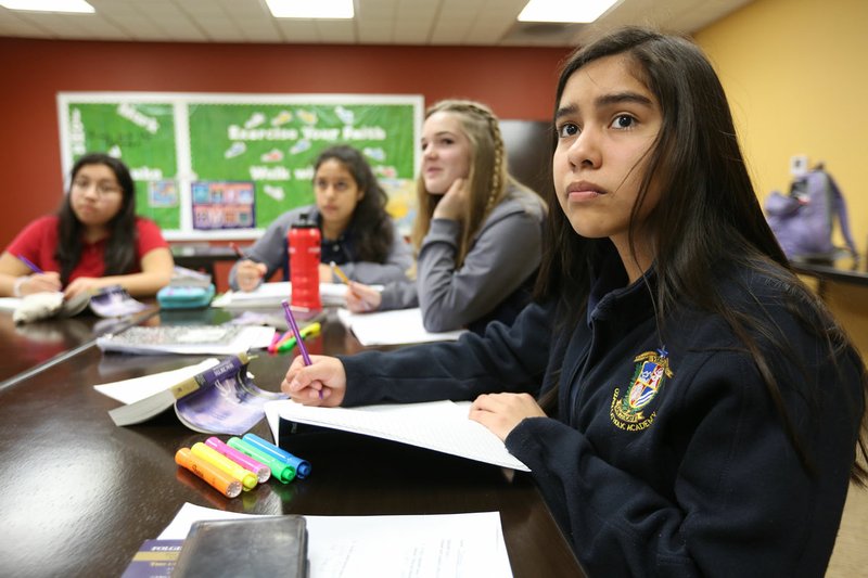 Stefany Mendoza (right), a freshman at Ozark Catholic Academy, listens to John Rocha, head of school, Tuesday give an introduction to William Shakespeare during Humane Letters class at the school in Tontitown. An anonymous gift of $3 million to Ozark Catholic Academy will reduce tuition by half for kids who graduate from a Catholic elementary/middle school, part of the school's new Continuing Catholic Education program. Go to nwaonline.com/200312Daily/ and nwadg.com/photos for a photo gallery. (NWA Democrat-Gazette/David Gottschalk)