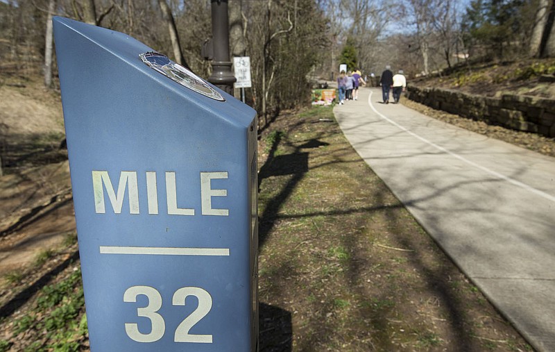 People walk Wednesday on the Razorback Greenway near Compton Gardens in Bentonville. (NWA Democrat-Gazette/Ben Goff)