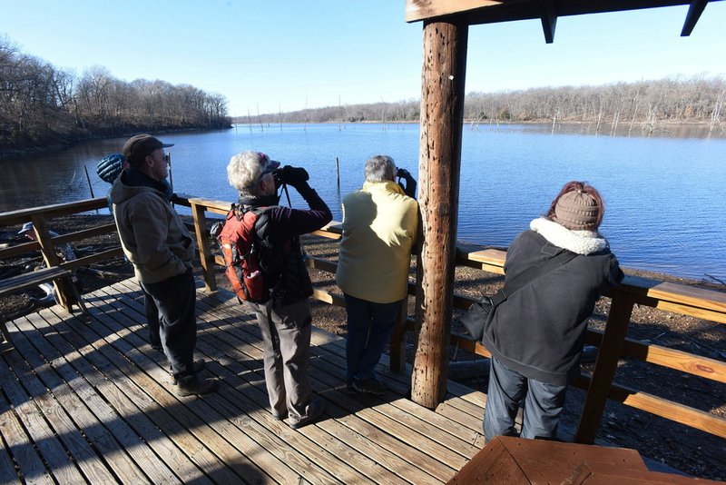 Visitors look at birds in February 2020 from a wildlife viewing pavilion at the Eagle Watch Nature Trail. The trail and lake are a popular with birders and hikers. Bird species should increase now that spring migration has started for all kinds of birds. (NWA Democrat-Gazette/Flip Putthoff)