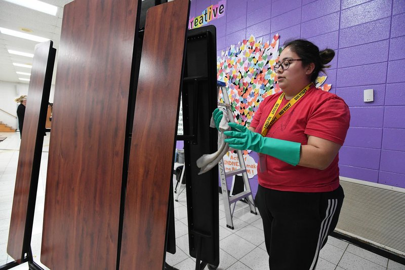 Lizzeth Solis, custodian at Walker Elementary School in Springdale, disinfects cafeteria tables Monday to help stop the spread of the coronavirus. Meals are being served to students at several locations in Springdale. Visit nwaonline.com/200317Daily/ for more images. (NWA Democrat-Gazette/J.T. Wampler)