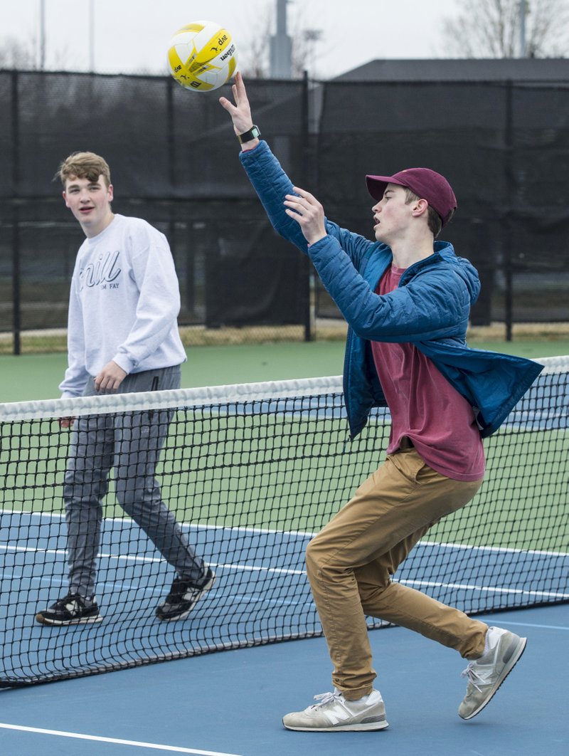 Alex Ezell, a student at West High School, returns the ball Tuesday while playing "phishball" with friends at the Memorial Park tennis courts in Bentonville. Phishball combines elements of volleyball, tennis and soccer. The students from Bentonville had free time after completing their online assignments for the day. All of their schools have moved to online instruction this week to prevent the spread of the covid-19. (NWA Democrat-Gazette/Ben Goff)