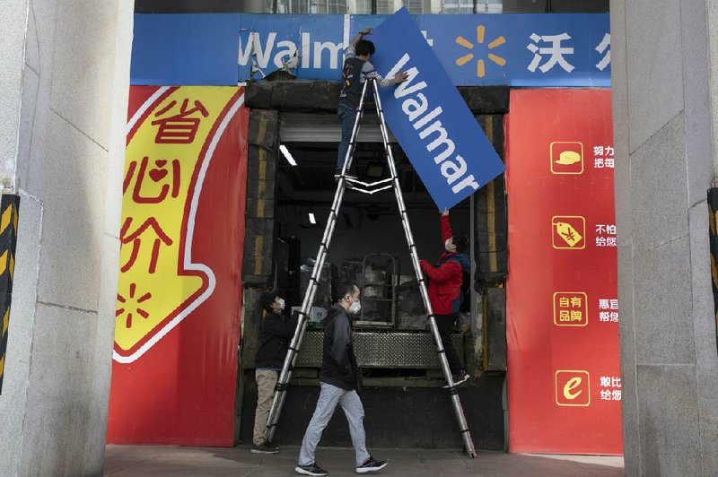 Workers replace signs outside a Walmart store in Beijing on Monday. China’s consumer spending and factory activity fell more than expected in January and February, the government said. (AP/Ng Han Guan) 
