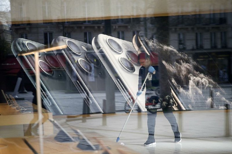 A worker sweeps inside the Apple Store on the Champs-Elysees in Paris on Sunday. French regulators fined Apple $1.2 billion on Monday over a non-compete agreement with two companies. (AP/Christophe Ena) 