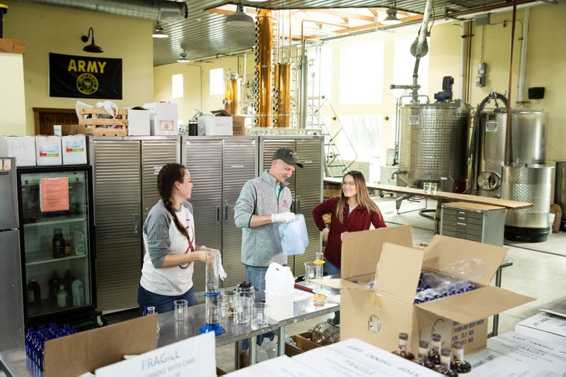 Caitlin Bagenstose (from left), Logan Snyder and his wife, Carly Snyder, bottle hand sanitizer Monday at the Eight Oaks Farm Distillery in New Tripoli, Pa. The distillery’s owner, Chad Butters, is tempo- rarily converting his operation into a production line for the suddenly hard-to-find, alcohol-based disinfectant. 
(AP/Matt Rourke) 
