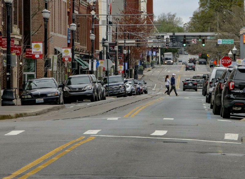 Pedestrians cross President Clinton Avenue around lunch hour in downtown Little Rock on Wednesday. The usually busy street was mostly devoid of traffic.  Full coverage of coronavirus at arkansasonline.com/coronavirus/.
(Arkansas Democrat-Gazette/John Sykes Jr.)
