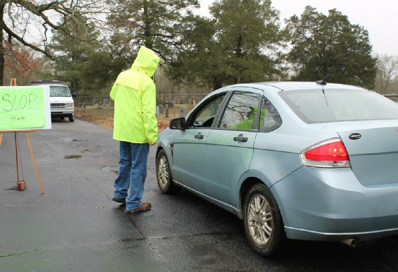 Rick Bryan instructs a person on the procedure for the new drive-thru format  of  the Bethlehem Food Pantry  on Monday,  put  in  place  at  the Greenbrier  church to reduce the risk of spreading covid-19 among recipients and church  volunteers.
(Arkansas Democrat-Gazette/Francisca Jones)